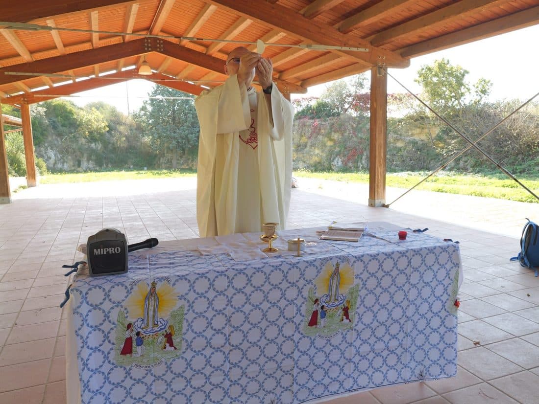 Le père Luc Mellet élève l’hostie pendant la messe célébrée en plein air.